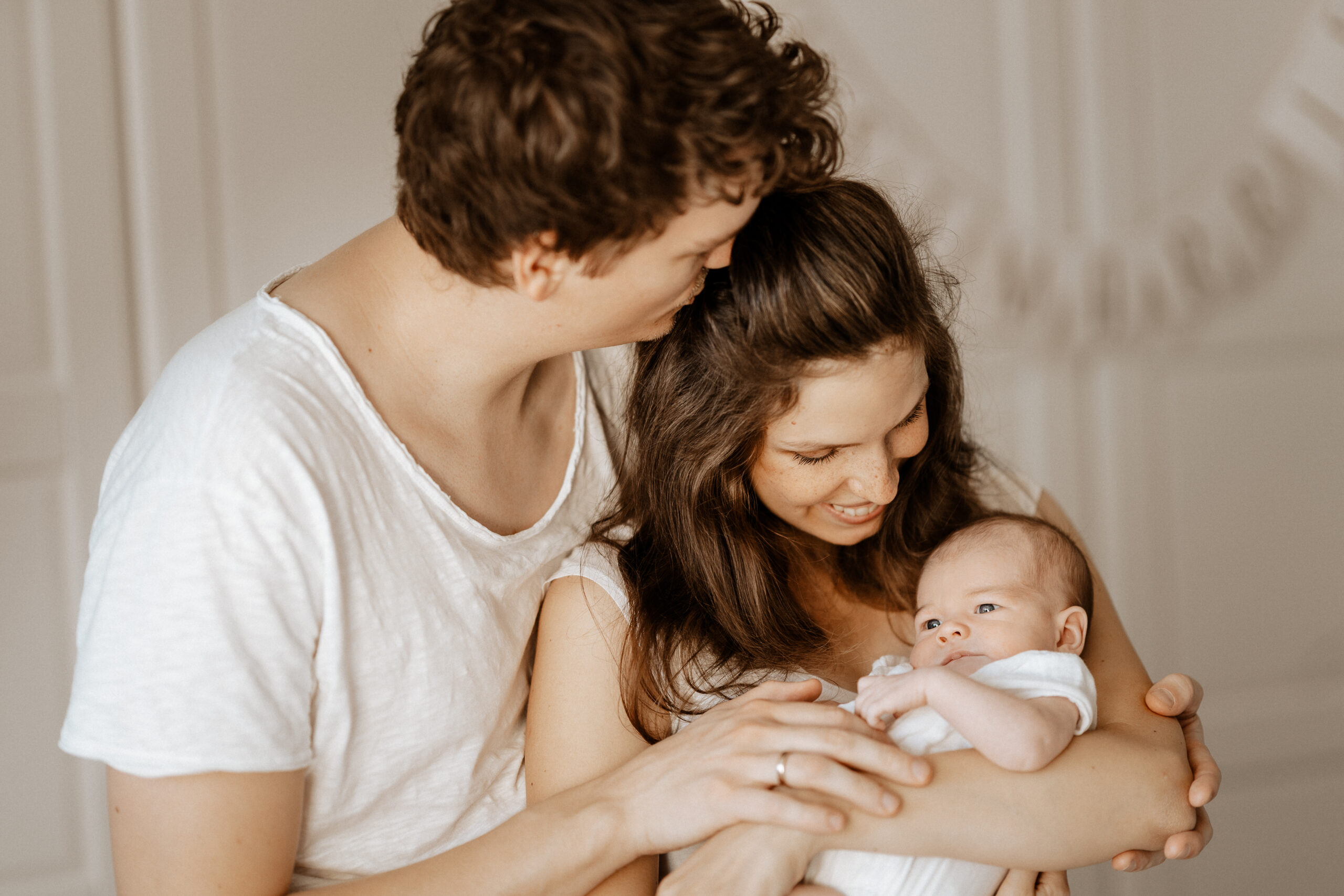 Hübsche, junge Familie mit Neugeborenen auf dem Arm.